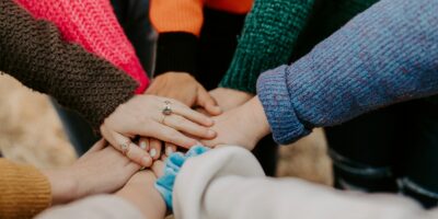 person in red sweater holding babys hand