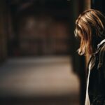 woman leaning against a wall in dim hallway