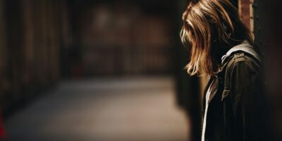 woman leaning against a wall in dim hallway